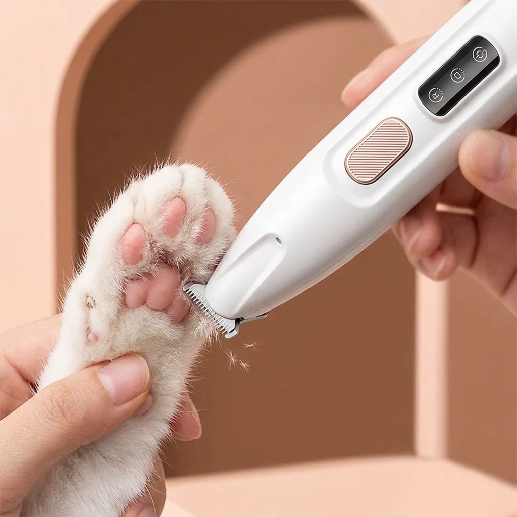 Person using a pet paw trimmer on a cat's paw with a neutral background